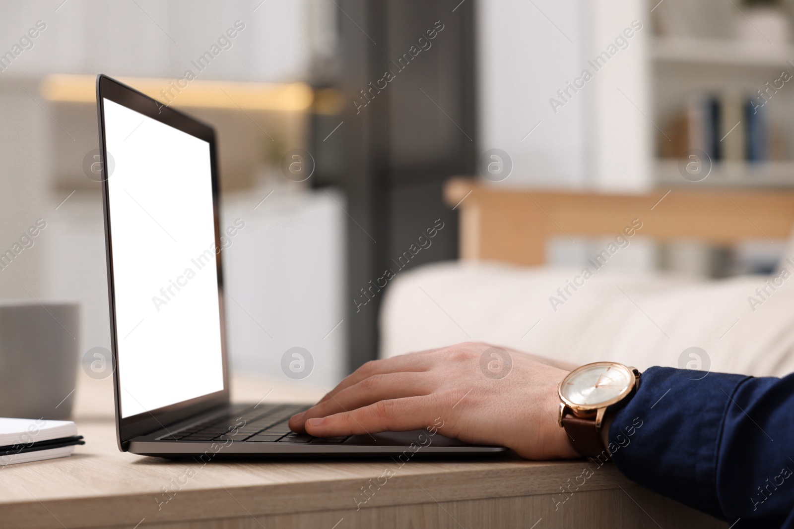 Photo of Man working on laptop at wooden desk indoors, closeup