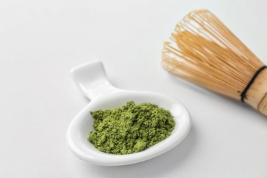 Powdered matcha tea and chasen on light background