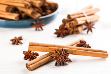 Aromatic cinnamon sticks and anise on white wooden table, closeup