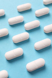 Photo of White pills on light blue background, above view