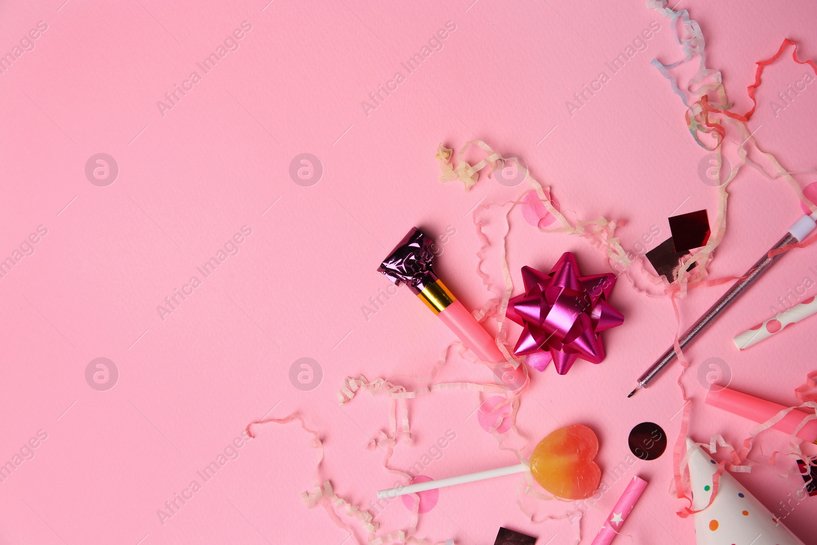 Photo of Party blower, lollipop and festive decor on pink background, flat lay. Space for text