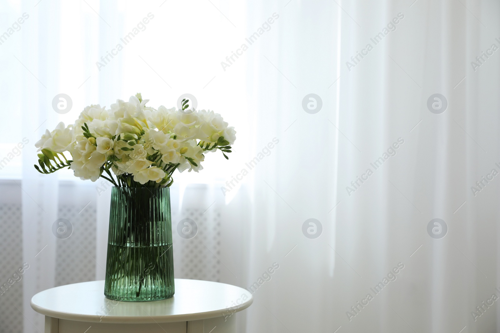 Photo of Beautiful bouquet with fresh freesia flowers on table indoors. Space for text