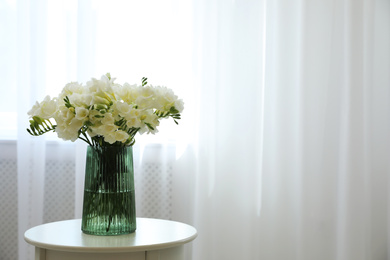 Photo of Beautiful bouquet with fresh freesia flowers on table indoors. Space for text