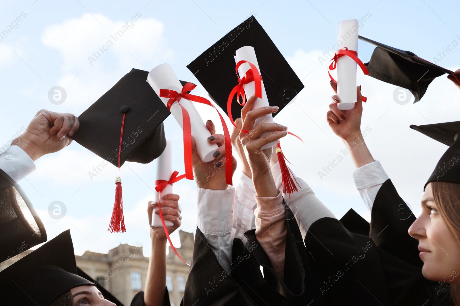 Photo of Group of students with diplomas outdoors. Graduation ceremony