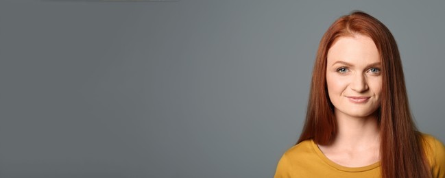 Image of Candid portrait of happy young woman with charming smile and gorgeous red hair on grey background, space for text. Horizontal banner design