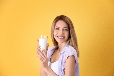 Beautiful young woman drinking milk on color background