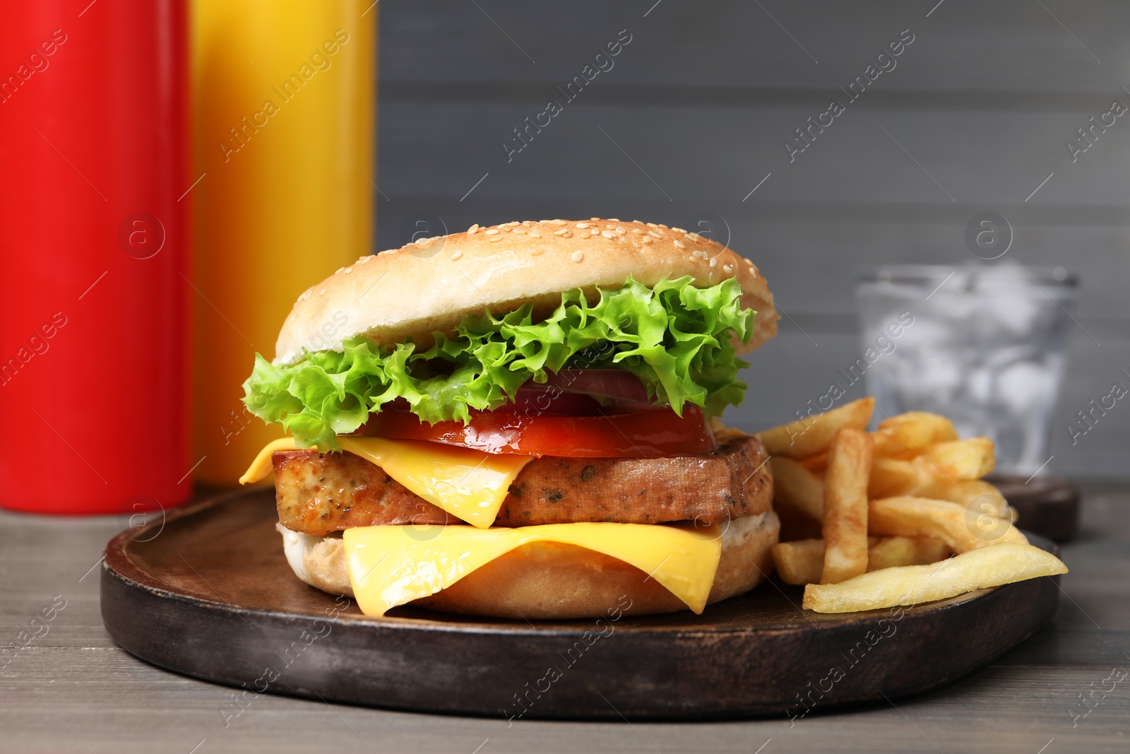 Photo of Delicious tofu burger served with french fries on grey wooden table