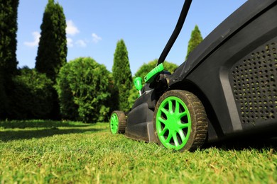 Lawn mower on green grass in garden, closeup. Space for text