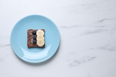 Photo of Toast with tasty nut butter, blueberries, banana and nuts isolated on white marble table, top view. Space for text