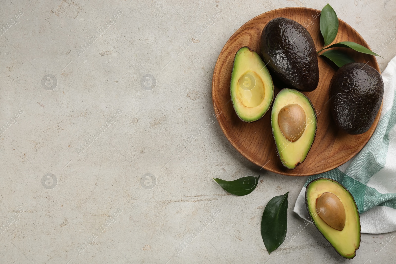 Photo of Whole and cut avocados on light table, flat lay. Space for text