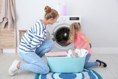 Photo of Little girl helping her mother to do laundry at home