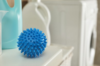 Photo of Dryer ball and laundry detergents on white table indoors, closeup