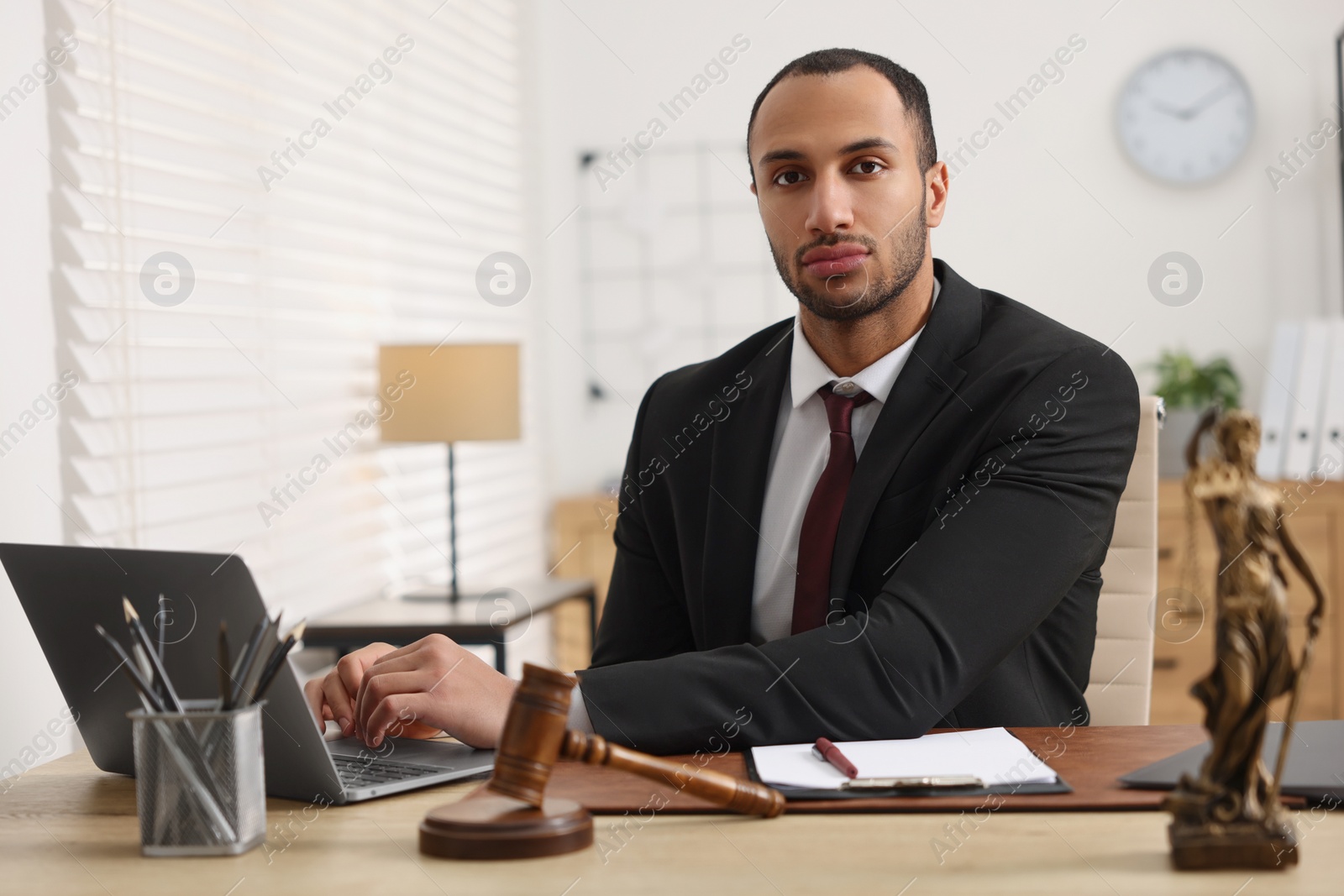 Photo of Serious lawyer working with laptop at table in office