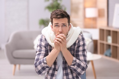 Photo of Sad young man suffering from cold on blurred background