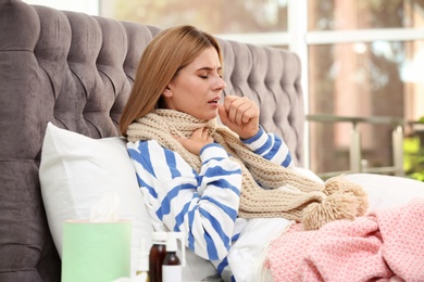 Woman suffering from cough and cold in bed at home