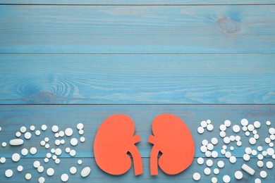 Photo of Paper cutout of kidneys and pills on blue wooden table, flat lay. Space for text
