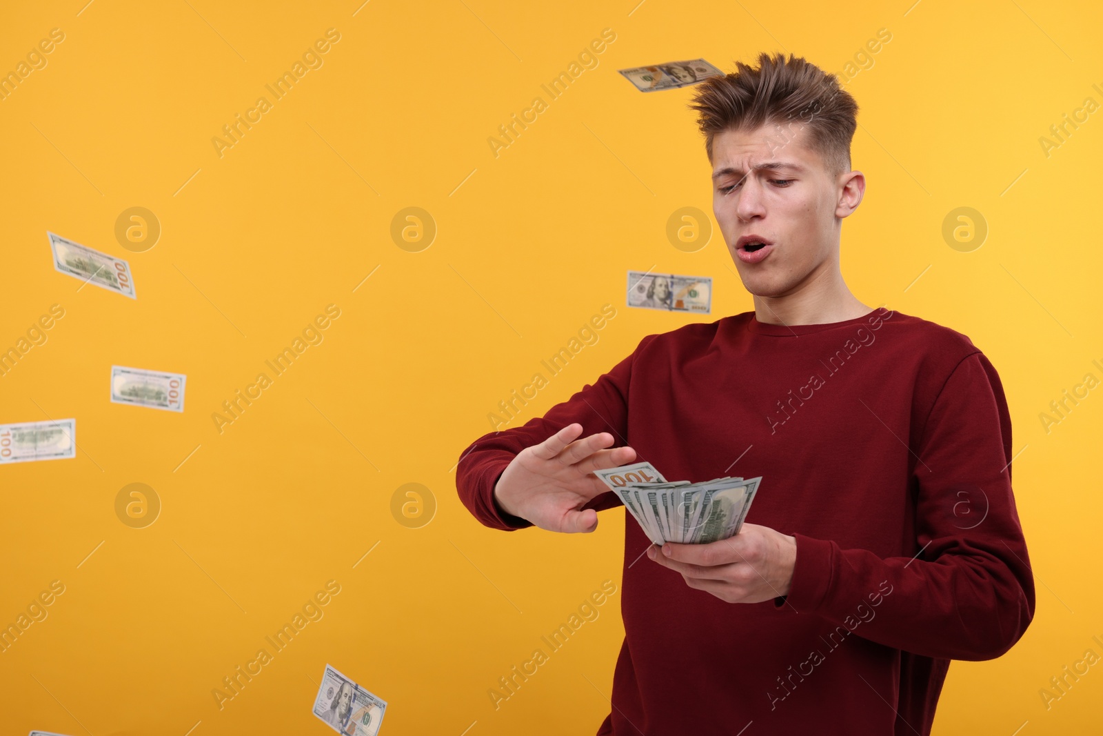 Photo of Handsome man throwing dollar banknotes on yellow background