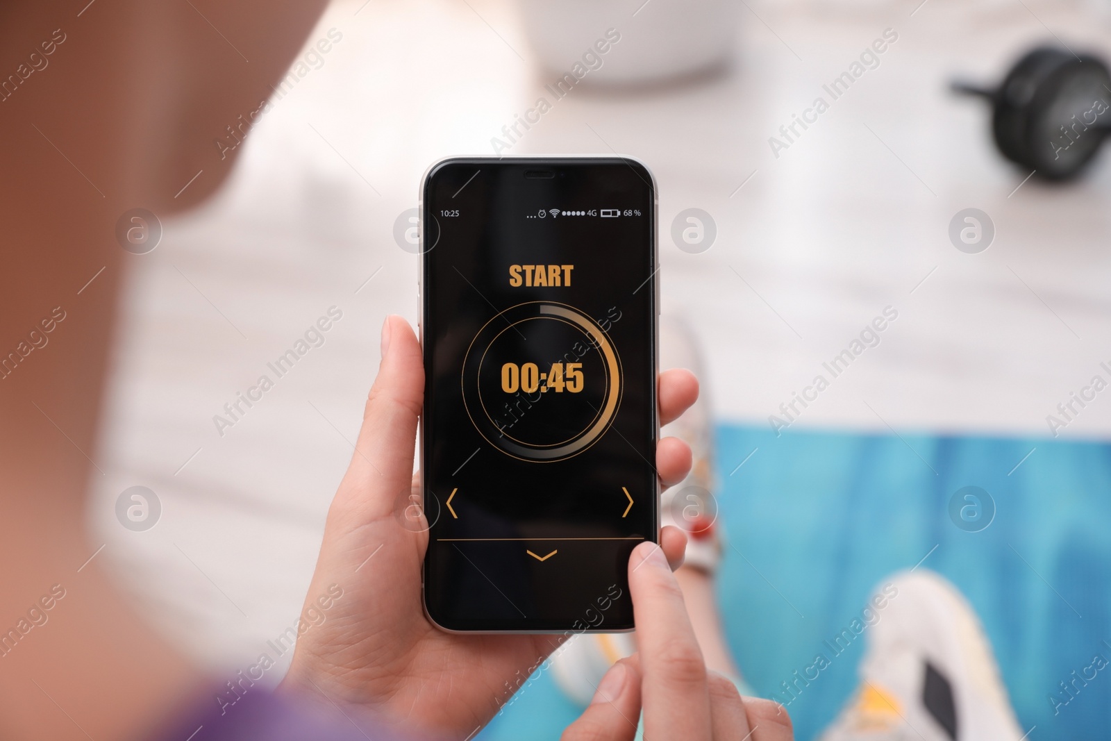 Photo of Young woman using fitness app on smartphone indoors, closeup