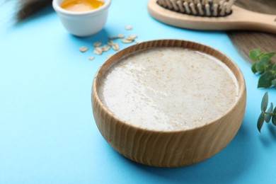 Photo of Homemade hair mask, ingredients and brush on light blue background