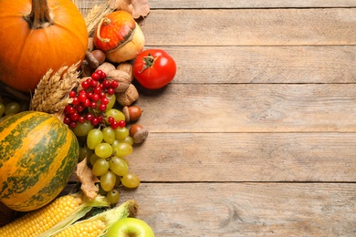 Photo of Flat lay composition with autumn vegetables and fruits on wooden background, space for text. Happy Thanksgiving day