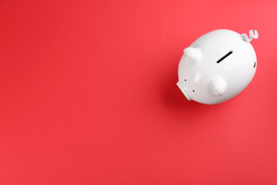 Photo of White piggy bank on red background, top view. Space for text