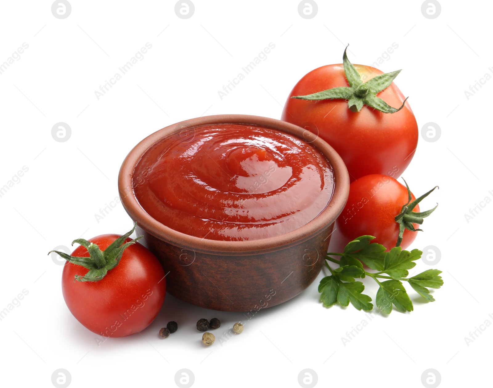 Photo of Tasty ketchup in bowl, parsley, peppercorns and fresh tomatoes isolated on white