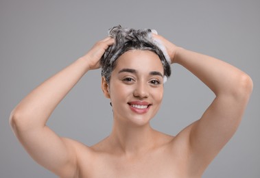 Photo of Portrait of beautiful happy woman washing hair on grey background