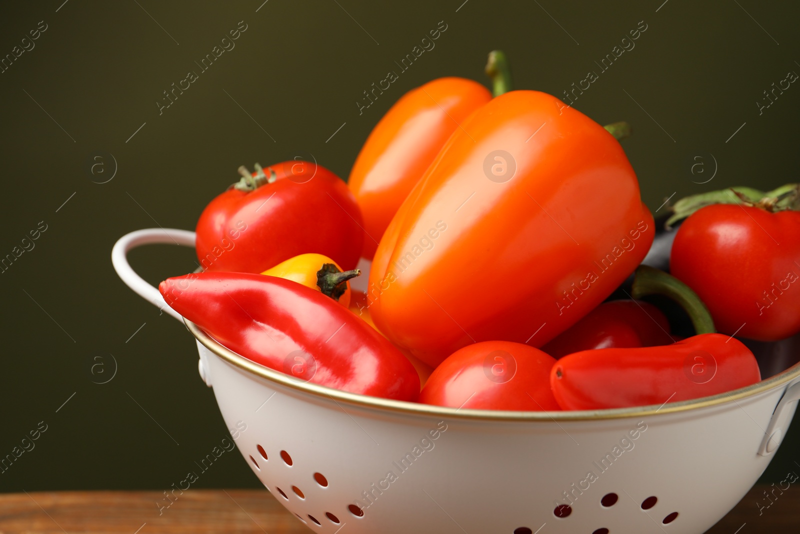 Photo of Colander with fresh vegetables on table, closeup