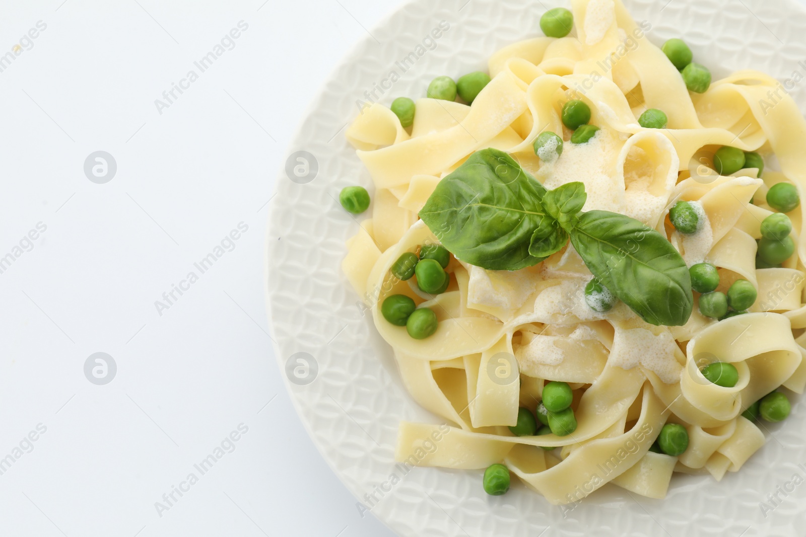 Photo of Delicious pasta with green peas, fresh basil and creamy sauce isolated on white, top view