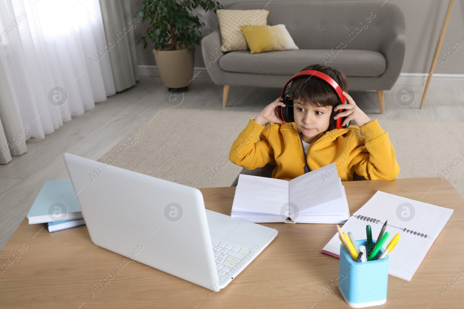 Photo of Cute little boy with modern laptop studying online at home. E-learning