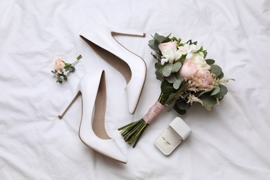 Photo of Flat lay composition with wedding high heel shoes and beautiful bouquet on white fabric