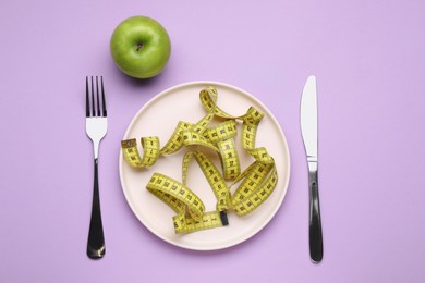 Photo of Measuring tape, cutlery and apple on violet background, flat lay. Weight loss concept
