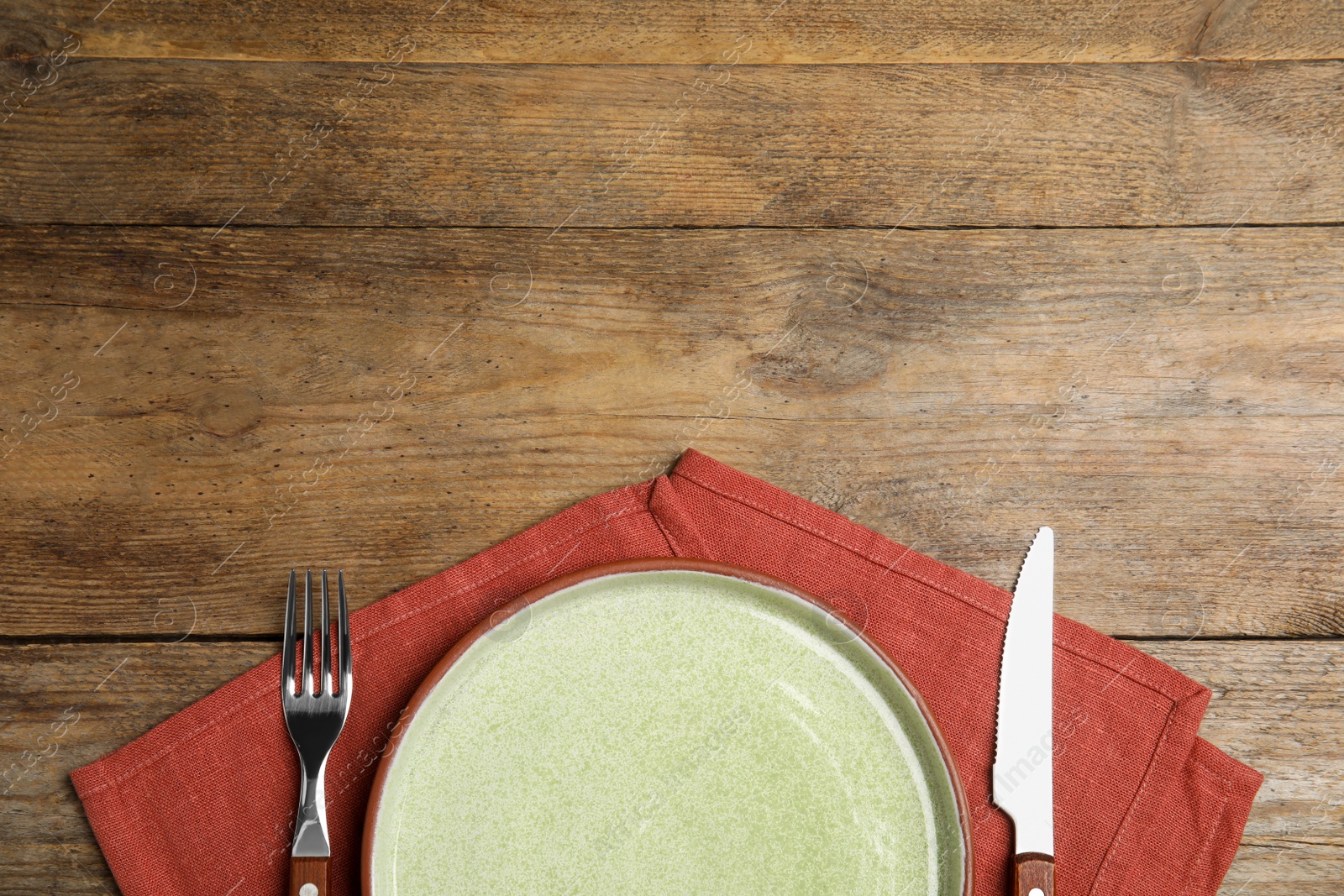 Photo of Empty plate, cutlery and napkin on wooden table, flat lay. Space for text