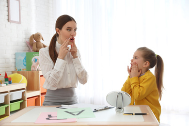Photo of Speech therapist working with little girl in office