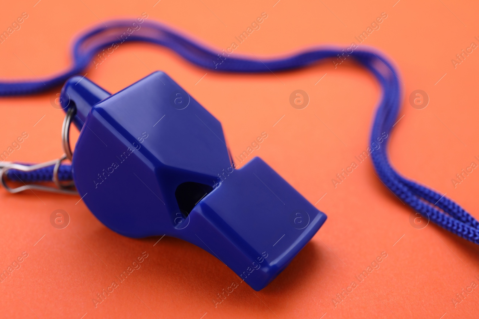 Photo of One blue whistle with cord on orange background, closeup