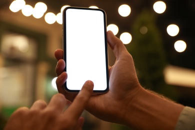 Man using modern mobile phone outdoors at night, closeup