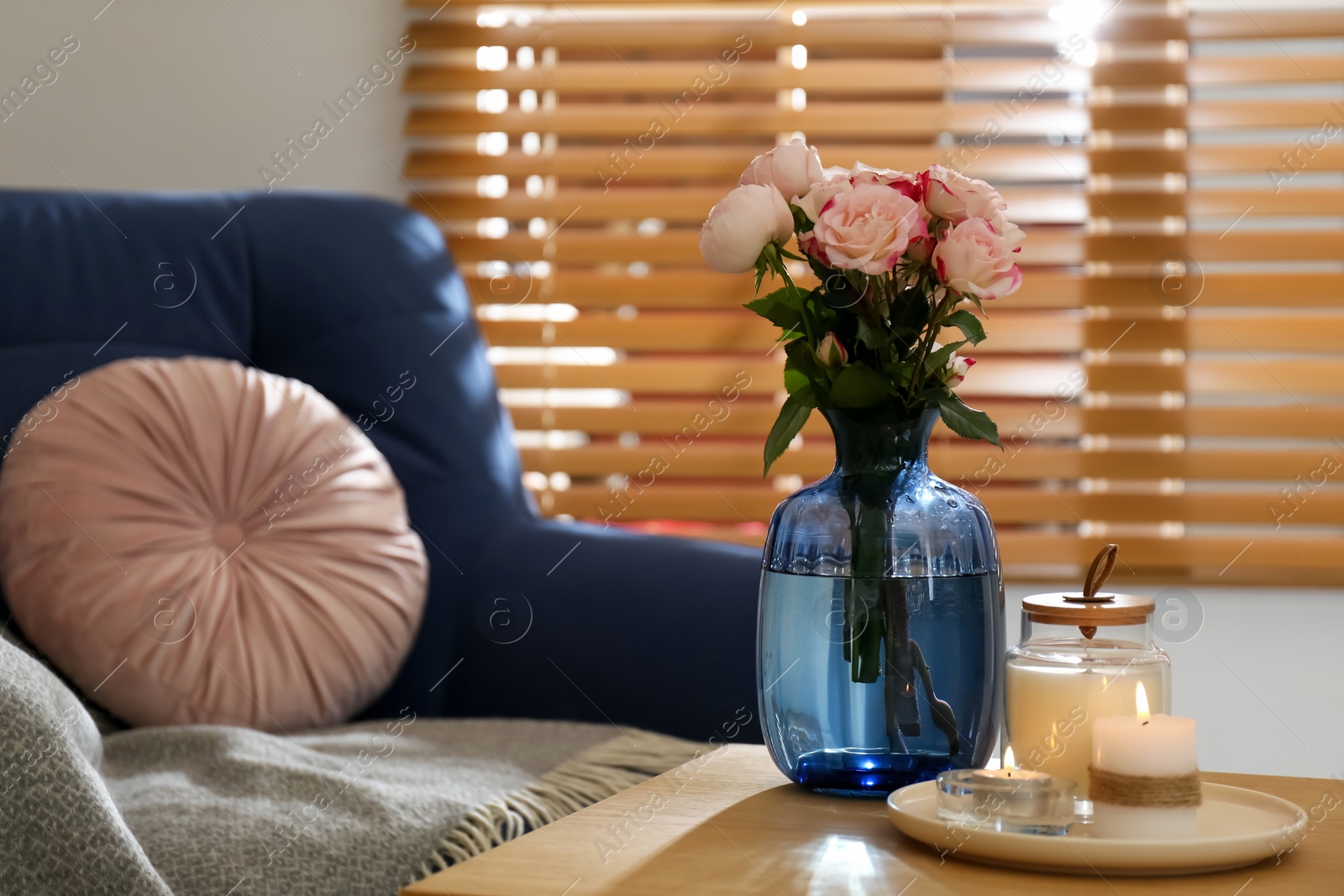 Photo of Vase with beautiful flowers and burning candles on wooden table indoors, space for text. Interior elements