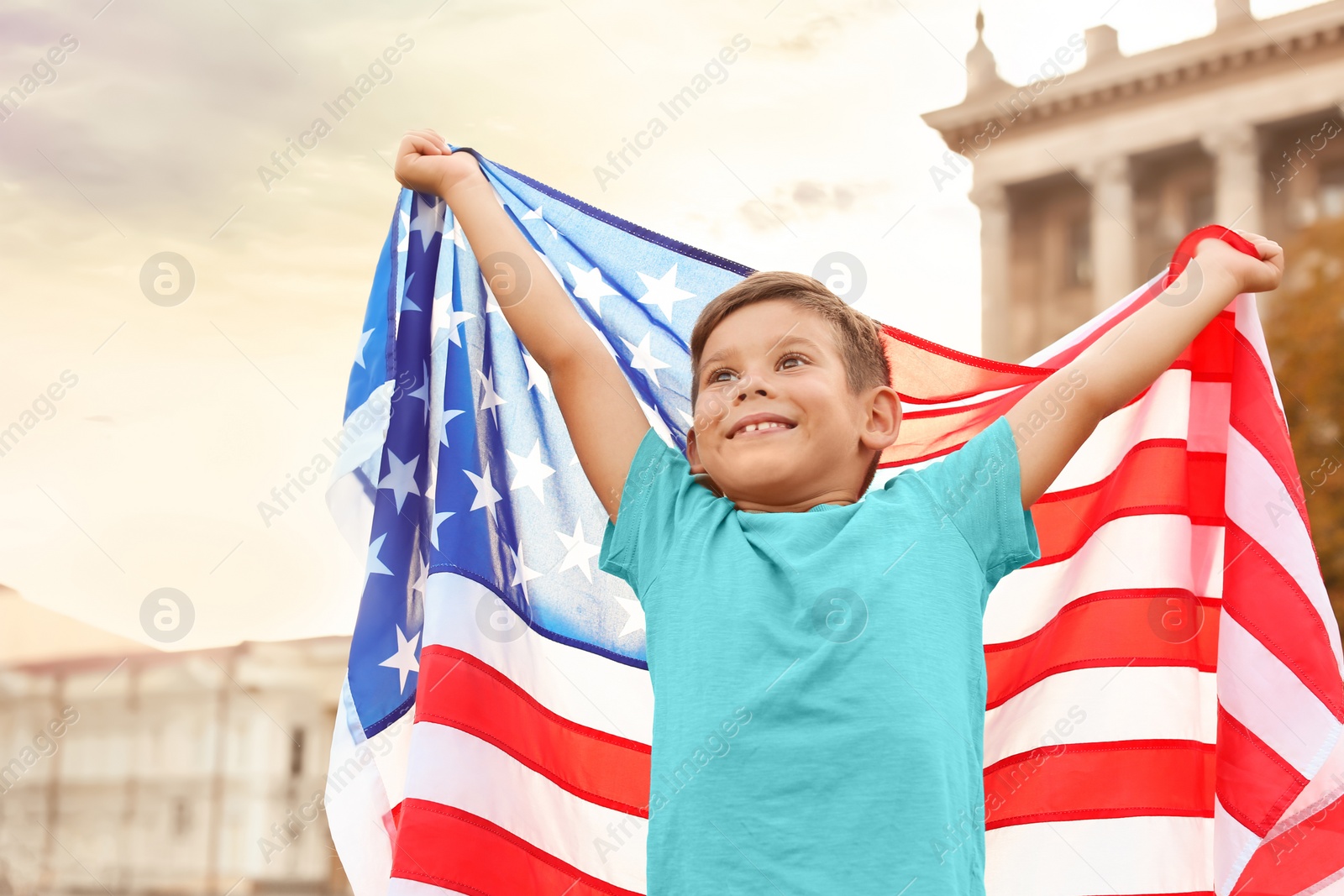 Photo of Cute little boy with American flag on city street