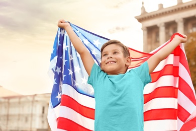Photo of Cute little boy with American flag on city street