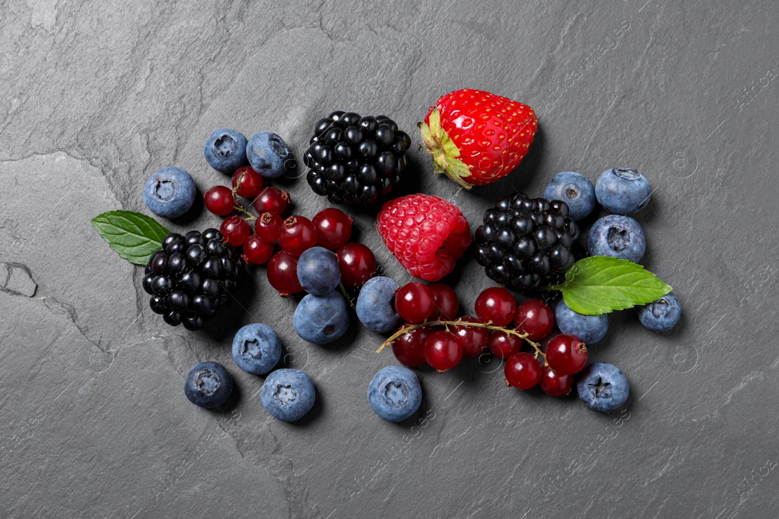 Photo of Many different fresh ripe berries on dark grey table, flat lay