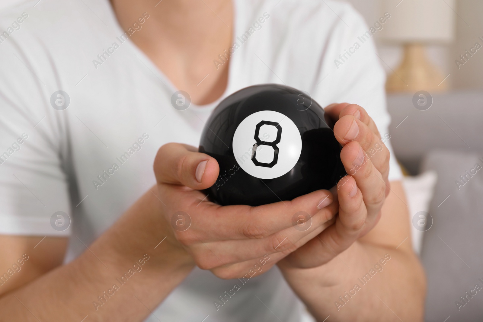 Photo of Man holding magic eight ball indoors, closeup