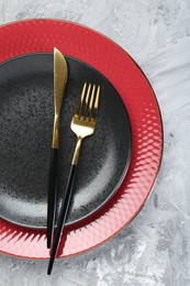 Photo of Clean plates and cutlery on gray textured table, top view