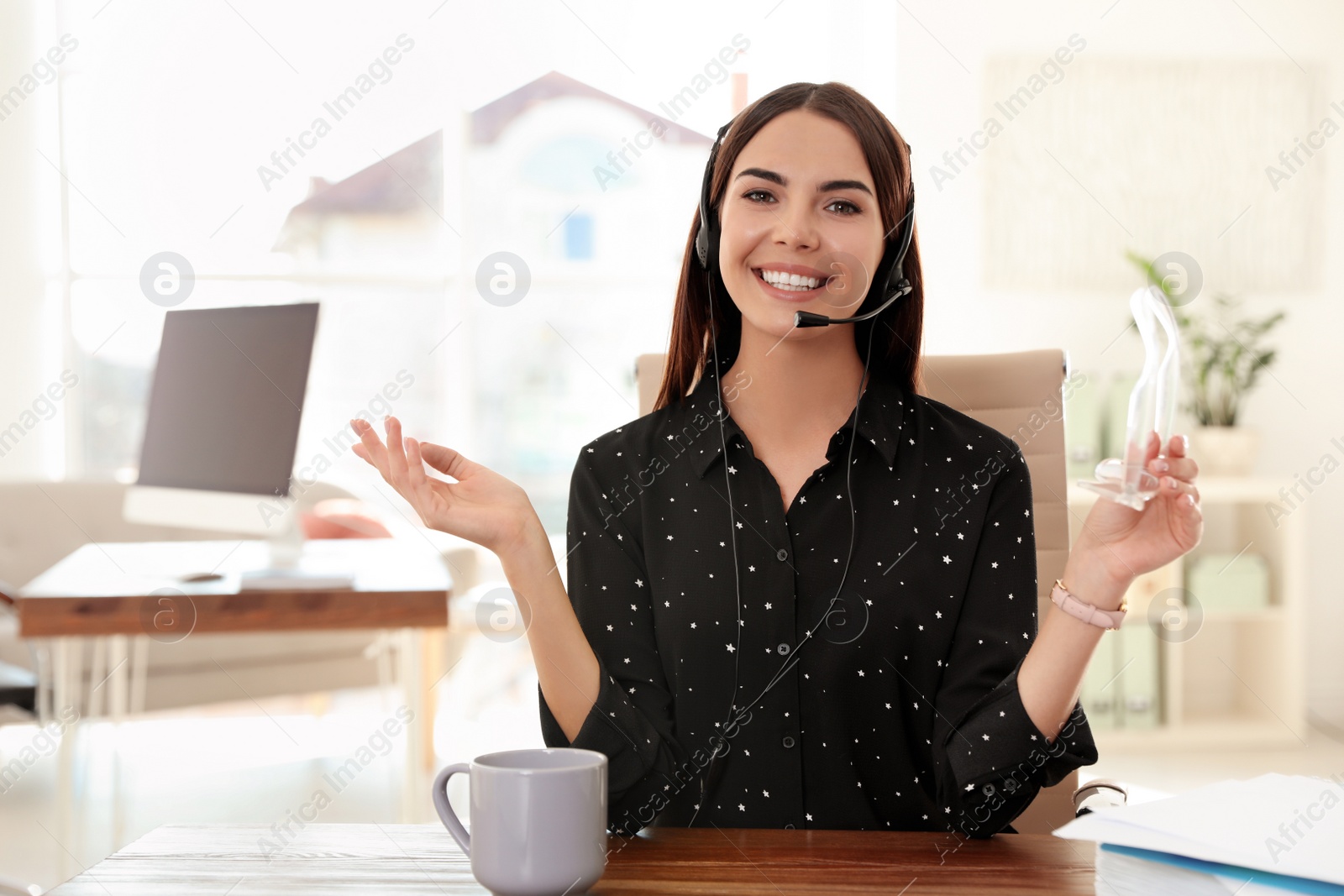 Photo of Young woman looking at camera and using video chat in home office. Space for text