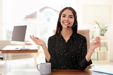 Young woman looking at camera and using video chat in home office. Space for text