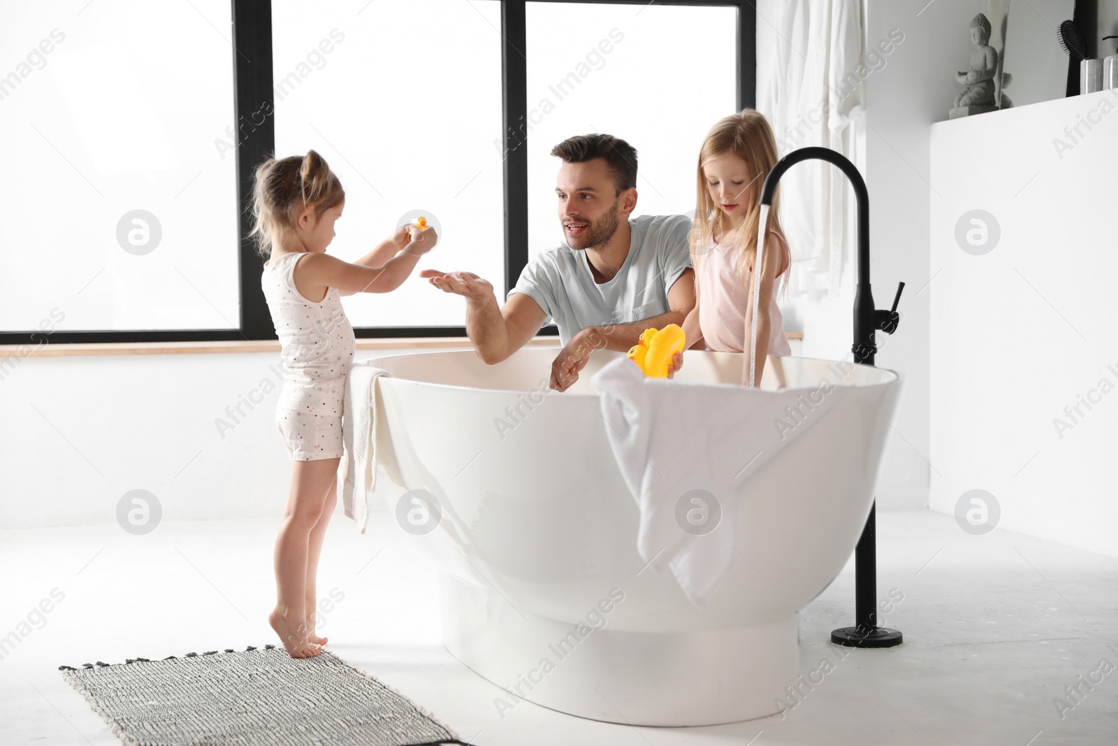 Photo of Young father with little daughters in bathroom