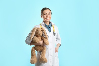 Photo of Pediatrician with toy bunny and stethoscope on turquoise background