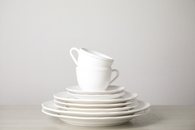 Stack of clean plates and cups on table against white background