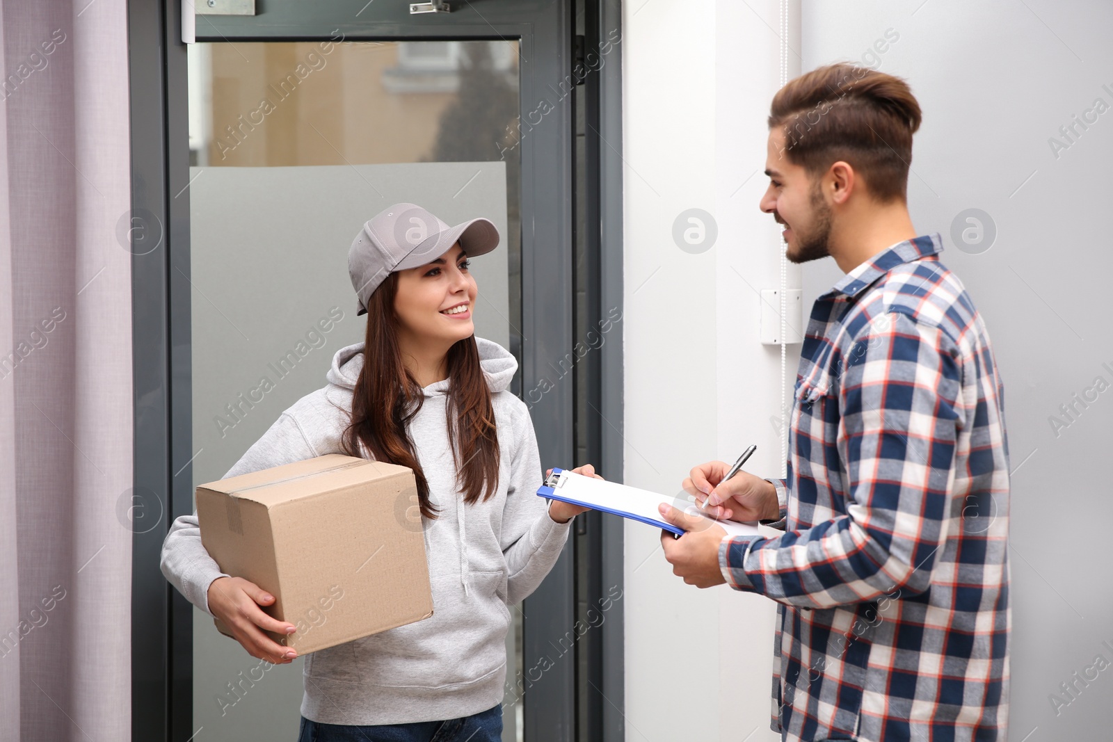 Photo of Man receiving parcel from delivery service courier indoors