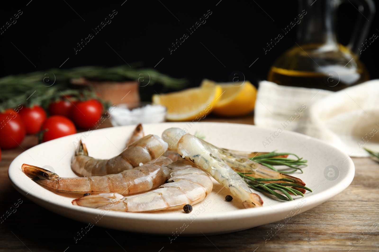 Photo of Fresh raw shrimps with rosemary and pepper on wooden table