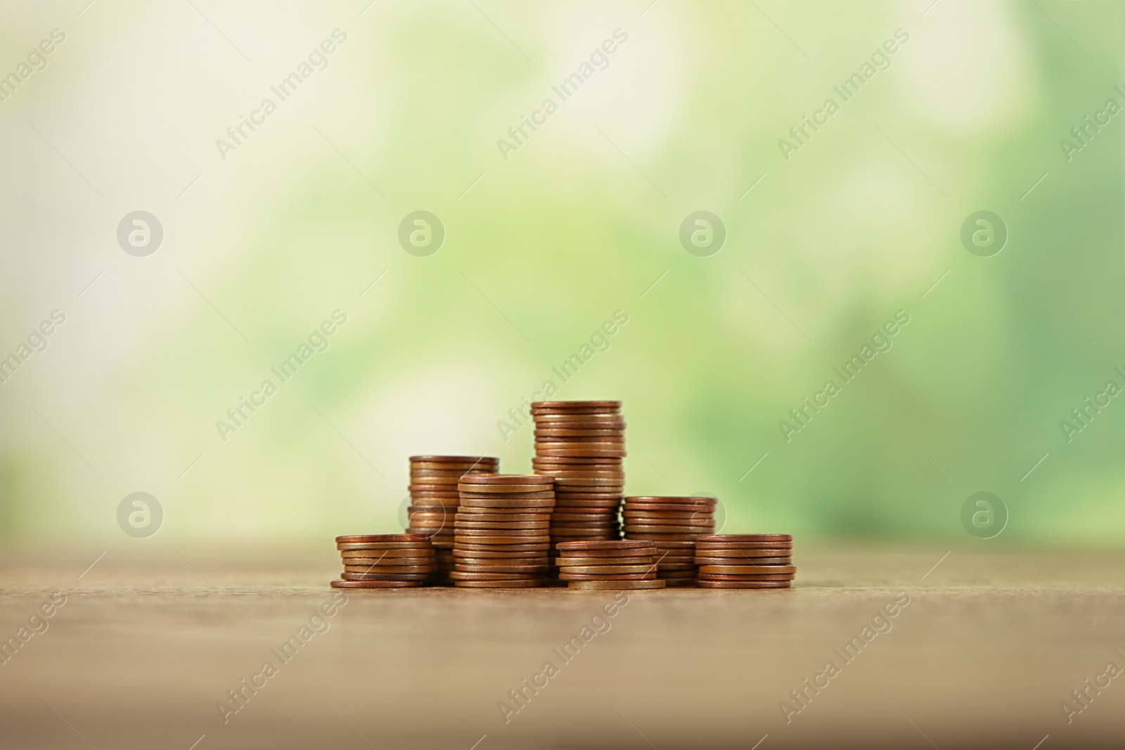 Photo of Stacks of coins on table against blurred background